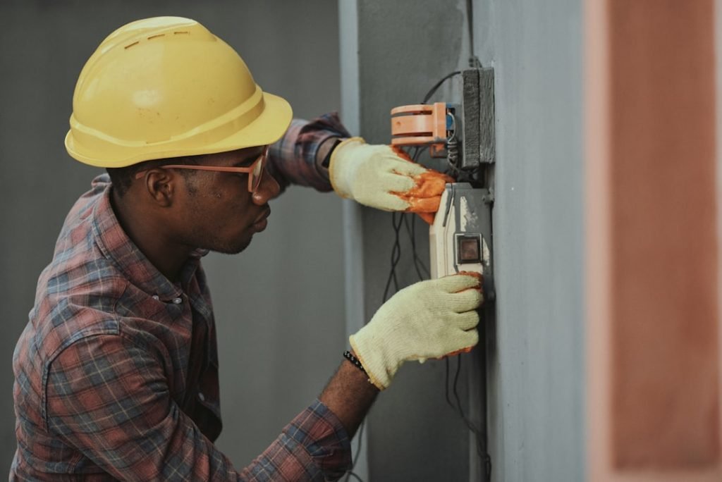 Portrait of a black man architect at a building site looking at camera. Confident civil engineering wearing a hardhat and eye goggles. Successful mature civil engineer at a construction site with open